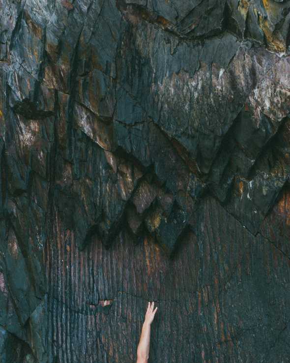 A hand tring to reach new level on a stone wall